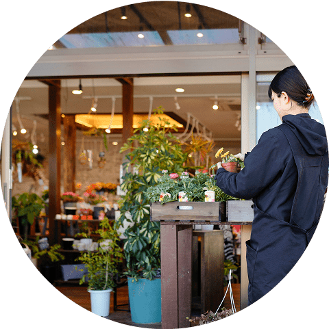 フラワーショップの店頭で鉢花を並べるスタッフ