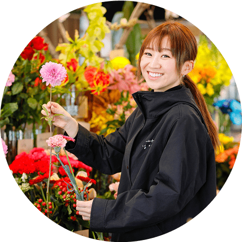 ピンクの花を持って笑顔を見せる花屋の女性スタッフ
