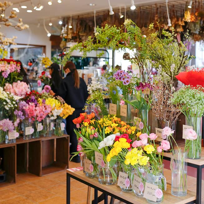 『はなも』の店内に並ぶ色とりどりの切り花。チューリップやフリージアなど、春らしい花がガラスの花瓶に美しくディスプレイされている