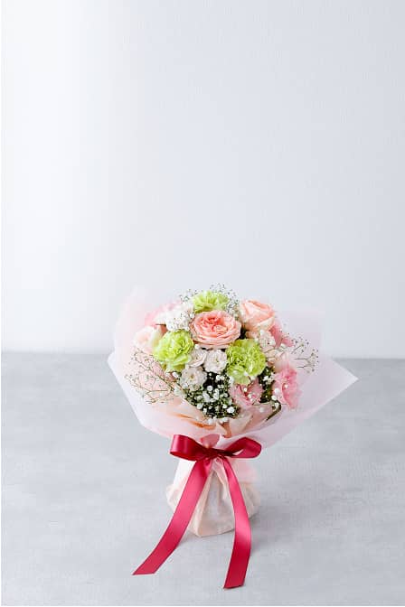 ピンクのバラとカーネーション、緑の花を組み合わせた華やかな花束。