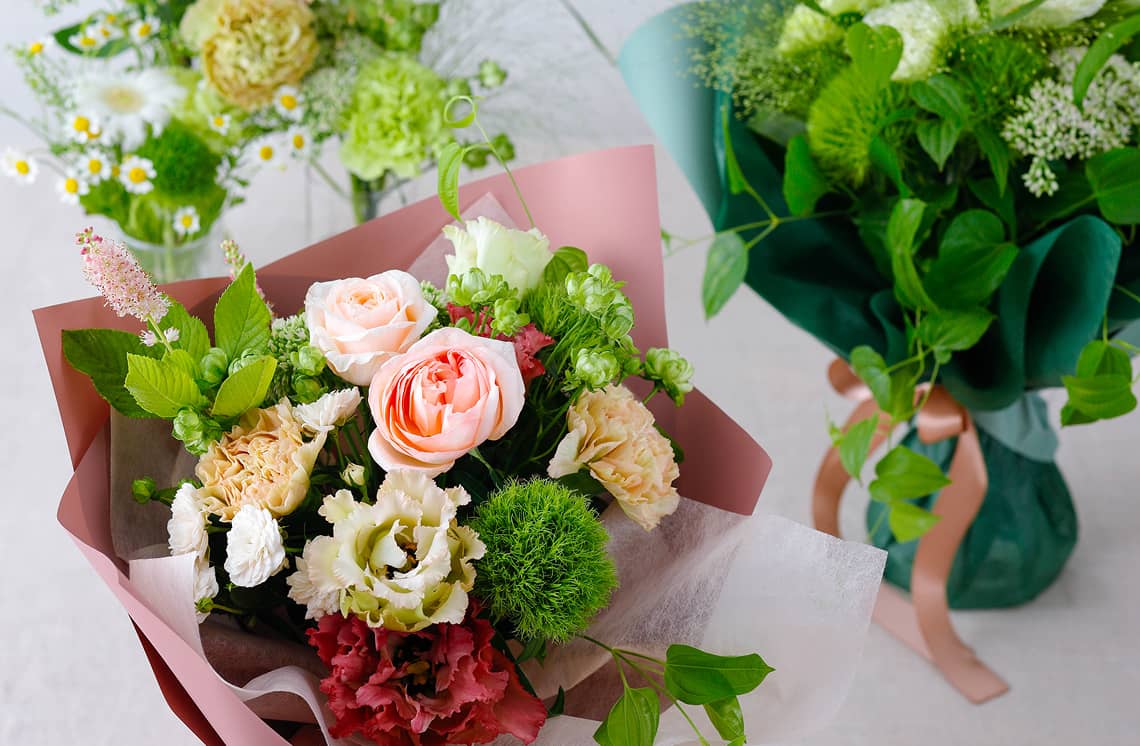 ピンクのラッピングに包まれたバラとカーネーションの花束